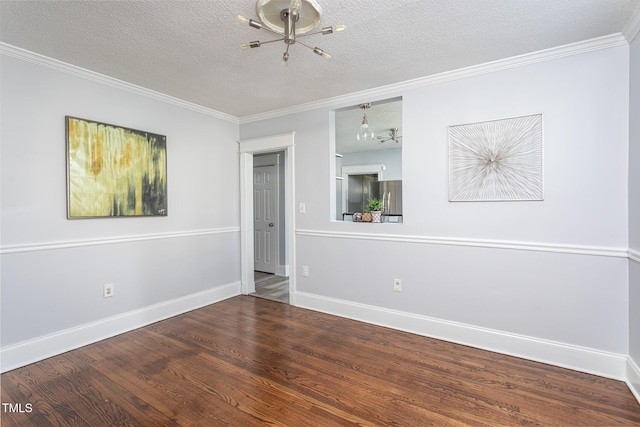 empty room with a textured ceiling, baseboards, wood finished floors, and crown molding