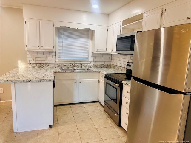 kitchen featuring a peninsula, appliances with stainless steel finishes, a sink, and white cabinets