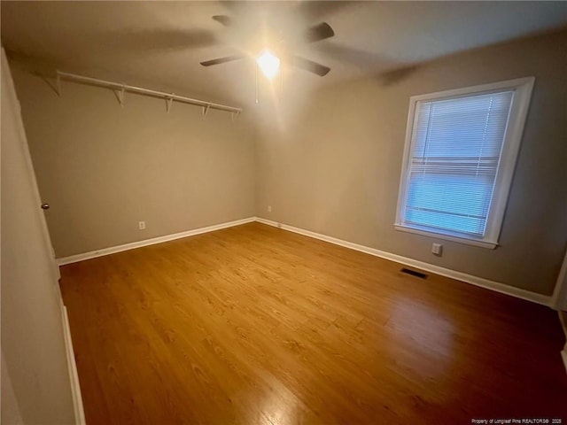 spare room featuring wood finished floors, visible vents, and baseboards