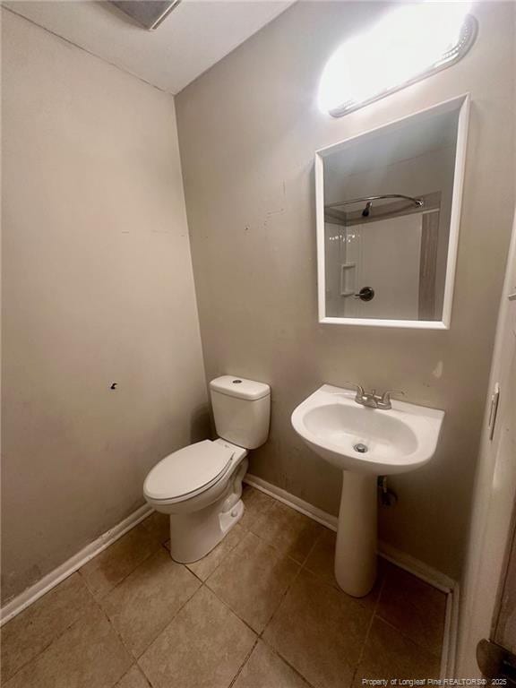 full bath with a shower, toilet, a sink, tile patterned flooring, and baseboards