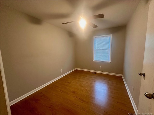 spare room with dark wood-type flooring, baseboards, and a ceiling fan