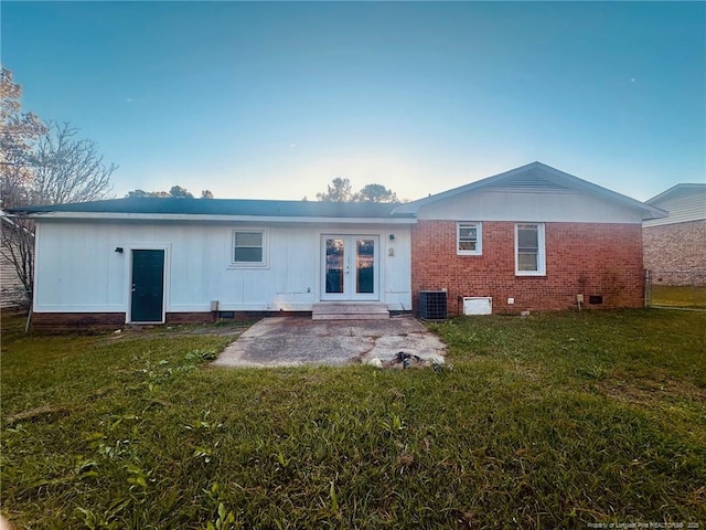 back of property with french doors, brick siding, a lawn, crawl space, and central AC