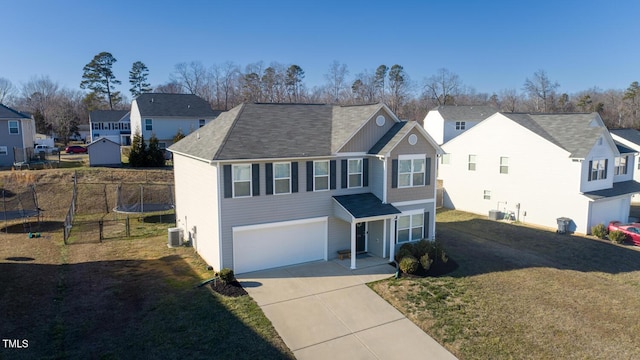 view of front of property with a garage, central air condition unit, a front lawn, and a trampoline