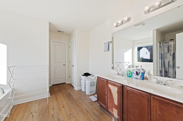 bathroom with hardwood / wood-style floors, a tub to relax in, and vanity