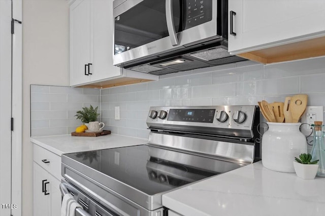 kitchen featuring stainless steel appliances, white cabinetry, light stone countertops, and decorative backsplash