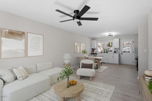 living room with sink, light hardwood / wood-style floors, and ceiling fan