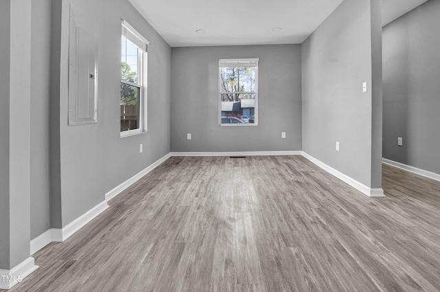 empty room featuring electric panel and light hardwood / wood-style floors