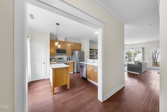 kitchen with pendant lighting, dark wood-type flooring, stainless steel appliances, ornamental molding, and a kitchen island