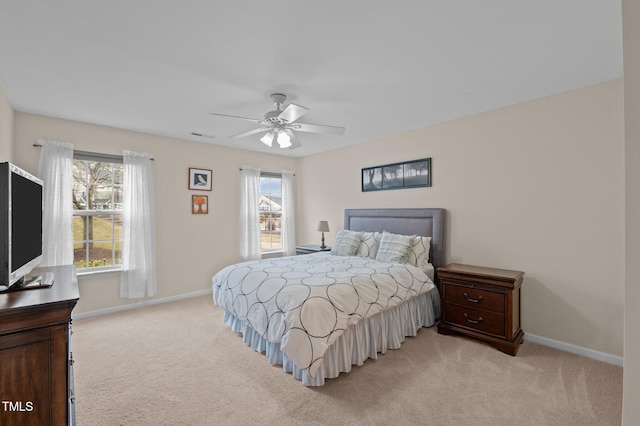 bedroom featuring ceiling fan, light colored carpet, and multiple windows