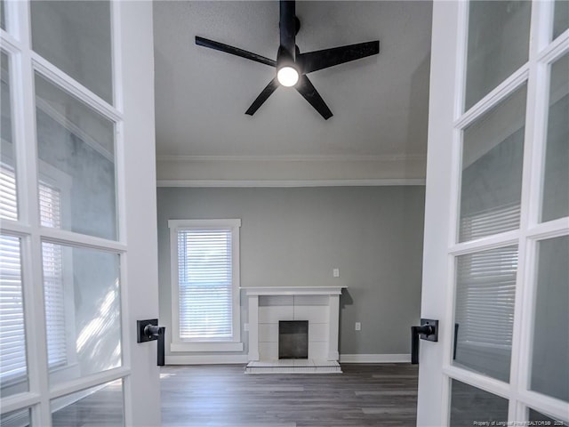 unfurnished living room with dark wood-type flooring, a tile fireplace, and ceiling fan