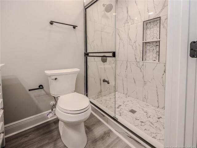 bathroom featuring toilet, a shower with door, and hardwood / wood-style flooring