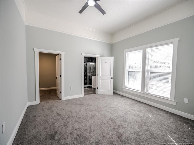 unfurnished bedroom with ceiling fan, carpet floors, stacked washer and dryer, a spacious closet, and a closet