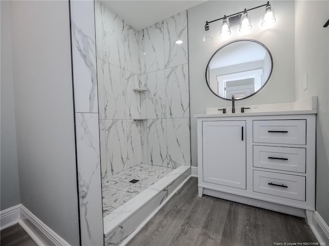 bathroom featuring wood-type flooring, vanity, and a tile shower