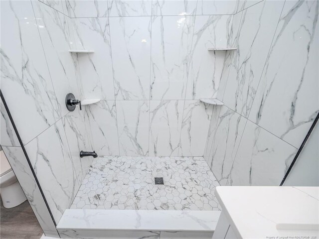 bathroom featuring toilet, vanity, and a tile shower