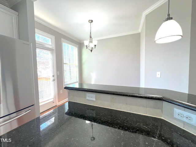 kitchen featuring stainless steel refrigerator, white cabinets, ornamental molding, and pendant lighting