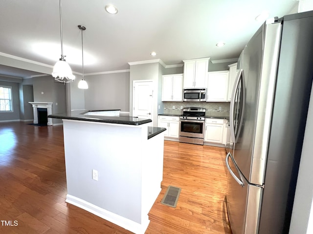 kitchen with stainless steel appliances, white cabinetry, backsplash, and decorative light fixtures