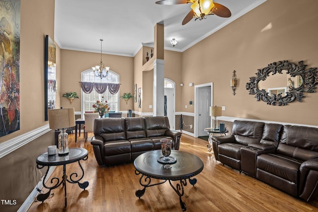 living room featuring ceiling fan with notable chandelier, ornamental molding, and wood-type flooring