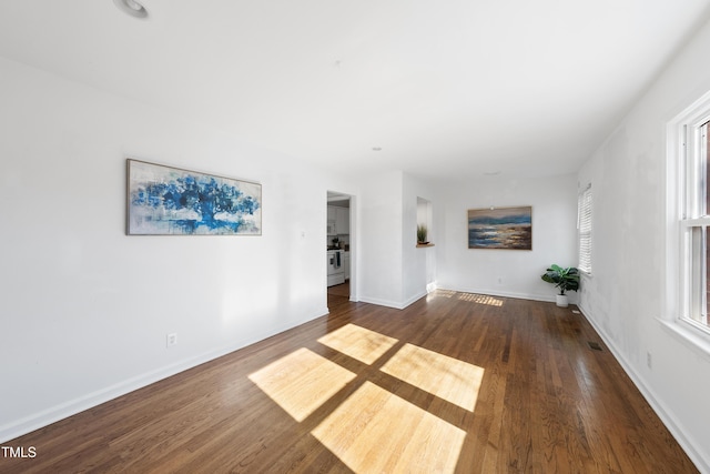 unfurnished living room featuring visible vents, baseboards, and dark wood finished floors