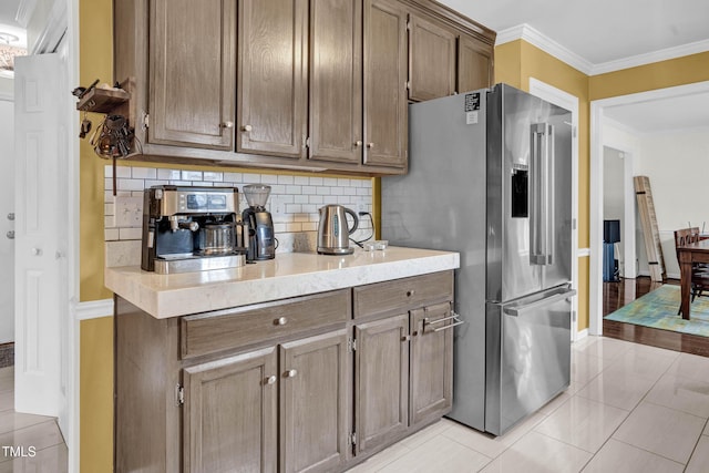 kitchen featuring tasteful backsplash, high quality fridge, ornamental molding, and light countertops