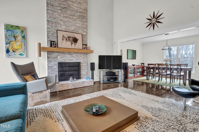 living area with a high ceiling, wood finished floors, and a glass covered fireplace