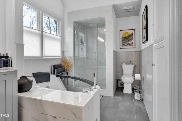 bathroom featuring toilet, vanity, tile walls, a bath, and tile patterned floors