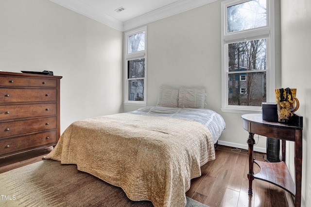 bedroom with baseboards, visible vents, wood finished floors, and ornamental molding