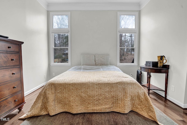 bedroom with crown molding, wood finished floors, and baseboards