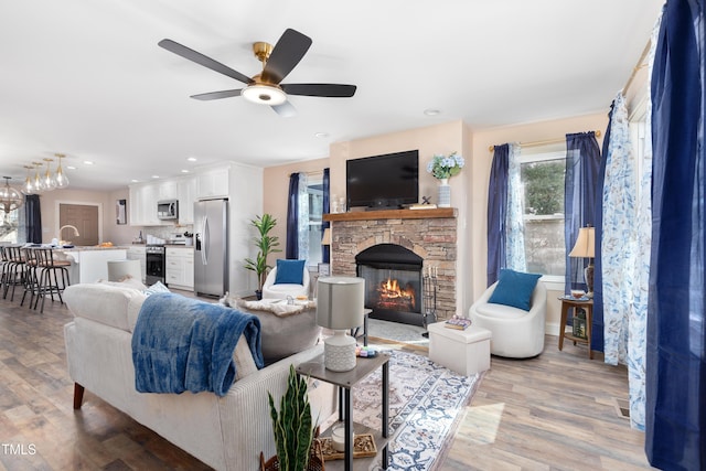 living room with a fireplace, light wood-type flooring, and ceiling fan