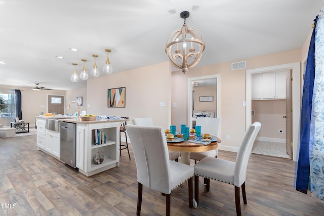 dining space with ceiling fan with notable chandelier, sink, and dark hardwood / wood-style floors