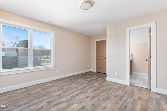 unfurnished bedroom with hardwood / wood-style floors and ensuite bathroom