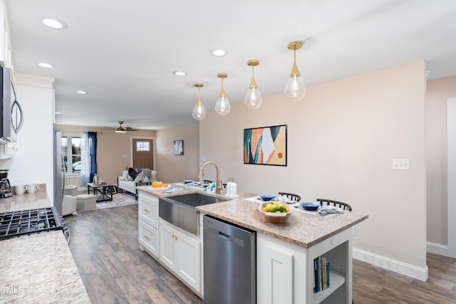 kitchen featuring appliances with stainless steel finishes, white cabinetry, sink, hanging light fixtures, and a kitchen island with sink