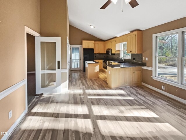 kitchen featuring light hardwood / wood-style floors, decorative backsplash, light brown cabinetry, a kitchen island, and sink