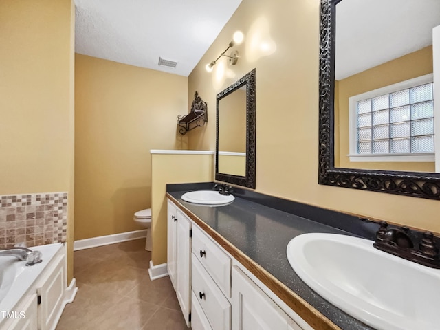 bathroom with a tub, toilet, vanity, and tile patterned flooring