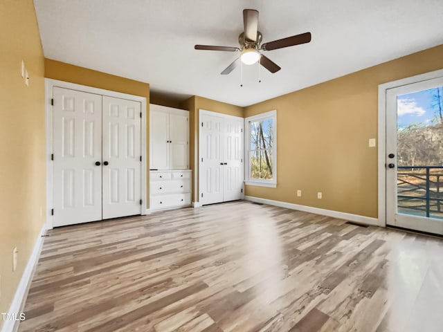 unfurnished bedroom featuring access to exterior, multiple windows, and two closets