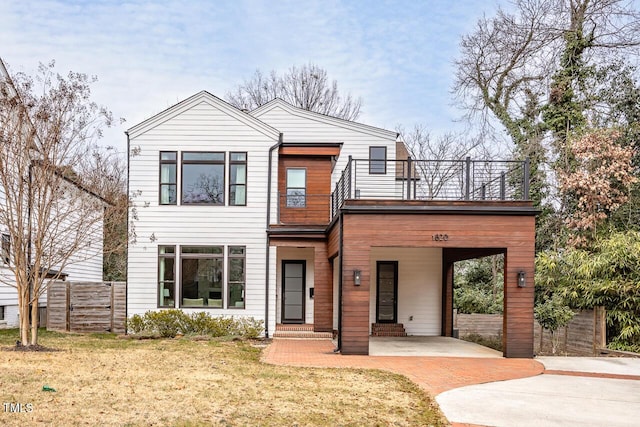 view of front of property with a balcony, a carport, and a front lawn