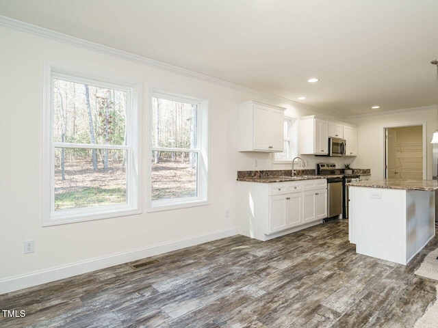 kitchen with stainless steel appliances, white cabinetry, crown molding, and dark stone counters