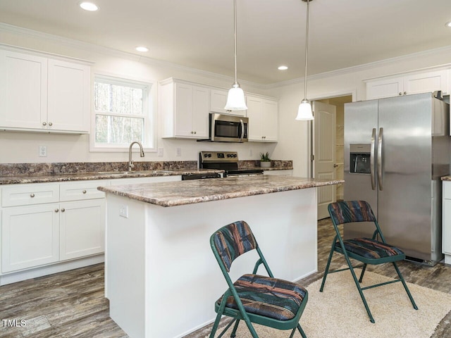 kitchen with a kitchen island, white cabinetry, appliances with stainless steel finishes, and hanging light fixtures