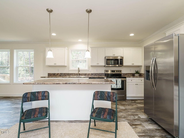 kitchen with pendant lighting, a breakfast bar, white cabinets, and appliances with stainless steel finishes