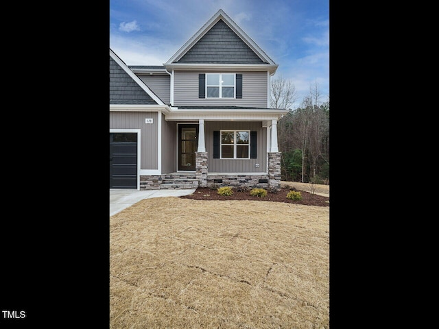 craftsman-style home with a porch, an attached garage, stone siding, and driveway