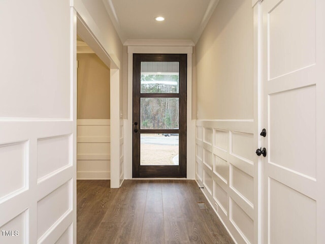 doorway with crown molding, dark wood finished floors, a wainscoted wall, recessed lighting, and a decorative wall