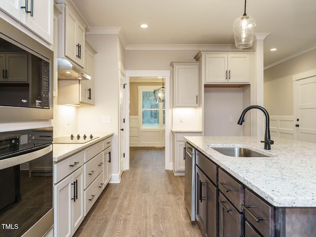 kitchen with dark brown cabinetry, sink, decorative light fixtures, appliances with stainless steel finishes, and light stone countertops