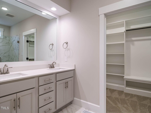 bathroom with a sink, a walk in closet, a marble finish shower, and visible vents