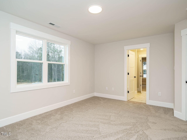 spare room with carpet flooring, baseboards, and visible vents