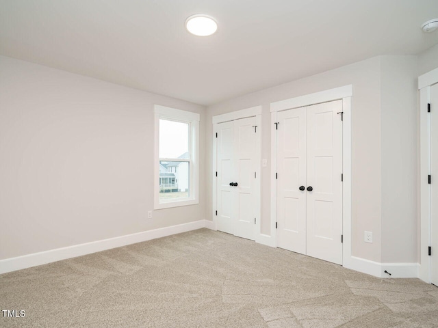 unfurnished bedroom featuring multiple closets and carpet flooring