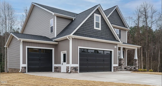 craftsman-style home with stone siding, a garage, driveway, and roof with shingles