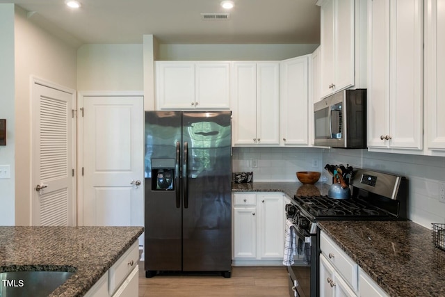 kitchen featuring white cabinets, decorative backsplash, dark stone counters, and stainless steel appliances