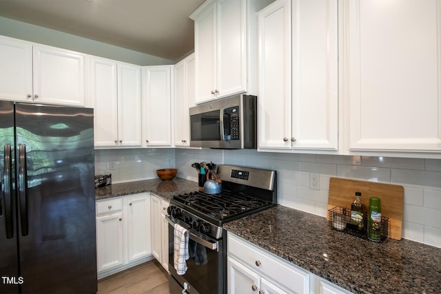 kitchen with white cabinetry, dark stone countertops, stainless steel appliances, and tasteful backsplash