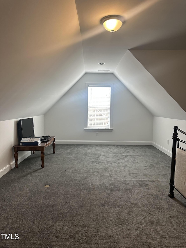 additional living space with vaulted ceiling and dark colored carpet