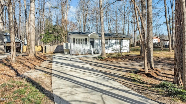 view of front of property featuring a porch, fence, and driveway