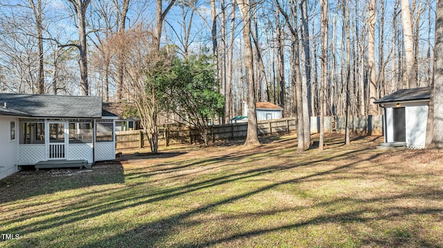 view of yard with a storage unit, an outdoor structure, a fenced backyard, and a sunroom